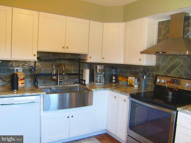 kitchen with white dishwasher, a sink, white cabinetry, wall chimney range hood, and stainless steel electric stove