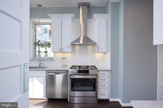 kitchen featuring light stone countertops, wall chimney range hood, white cabinetry, and stainless steel appliances