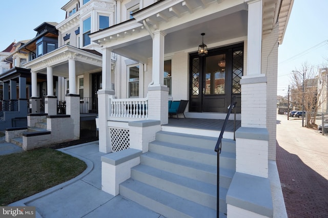 view of exterior entry featuring covered porch and brick siding