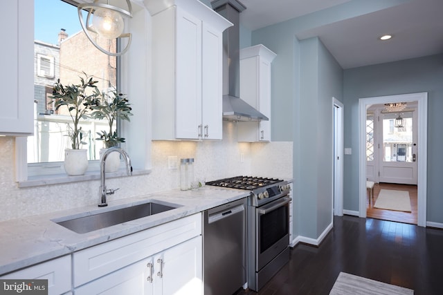 kitchen with appliances with stainless steel finishes, white cabinetry, wall chimney exhaust hood, and light stone countertops