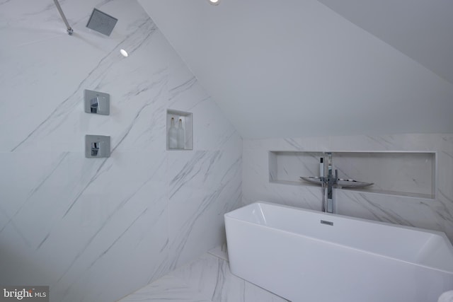 full bath with a freestanding tub, a marble finish shower, and vaulted ceiling