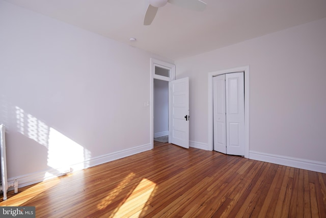 unfurnished bedroom with hardwood / wood-style flooring, ceiling fan, baseboards, and a closet