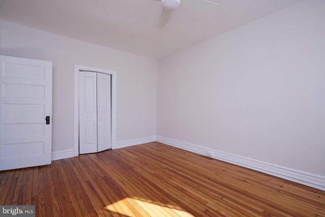 unfurnished bedroom featuring a ceiling fan, a closet, baseboards, and hardwood / wood-style floors