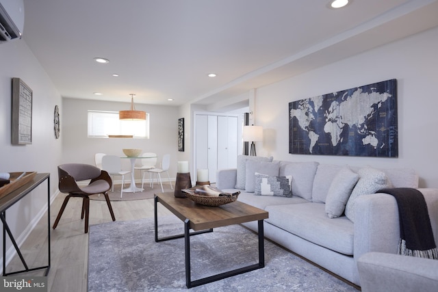 living area with light wood-style floors, recessed lighting, an AC wall unit, and baseboards