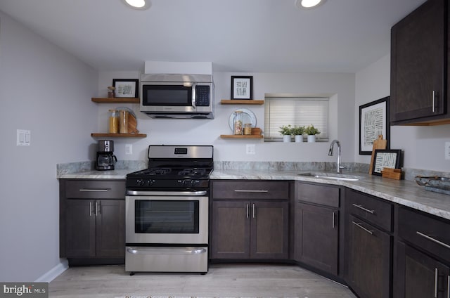 kitchen with stainless steel appliances, a sink, light wood-style floors, dark brown cabinets, and open shelves