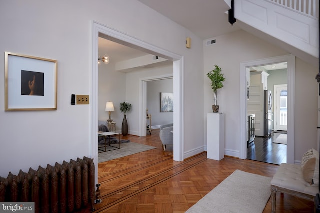 corridor with radiator, baseboards, and visible vents