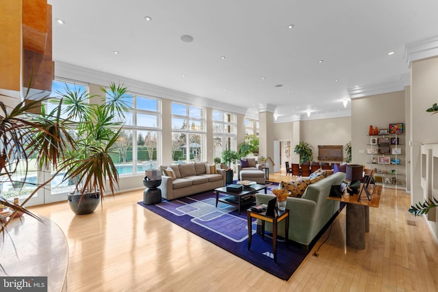 living room with light wood-style floors, crown molding, and recessed lighting