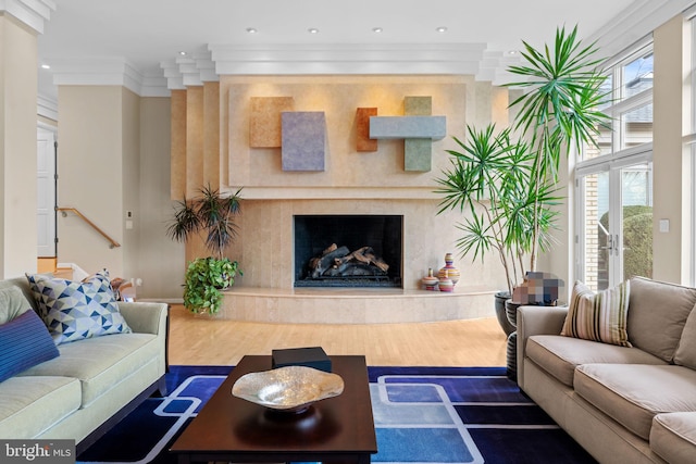 living room featuring a wealth of natural light, a high end fireplace, crown molding, and wood finished floors