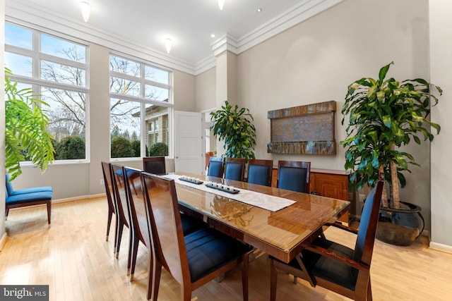 dining room featuring ornamental molding, light wood-style floors, and baseboards