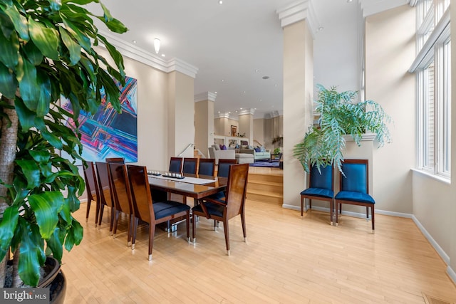 dining area featuring light wood-style floors, ornamental molding, and baseboards