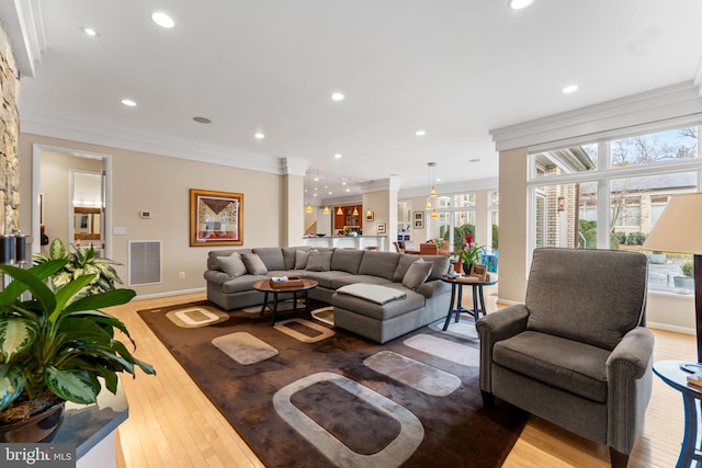 living area with ornamental molding, recessed lighting, visible vents, and light wood-style floors