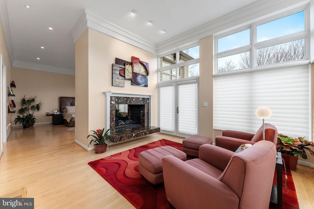 living room featuring baseboards, ornamental molding, wood finished floors, a fireplace, and recessed lighting