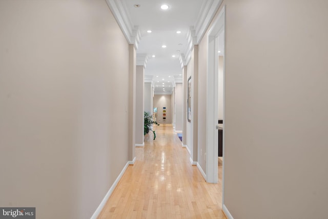 corridor featuring ornamental molding, recessed lighting, baseboards, and light wood finished floors