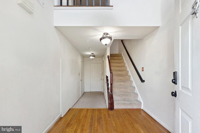 foyer entrance featuring stairway, light wood-style flooring, and baseboards