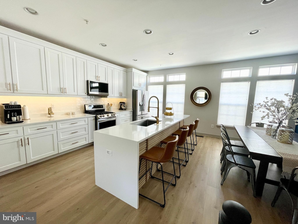 kitchen with a healthy amount of sunlight, light wood-style flooring, appliances with stainless steel finishes, and a sink