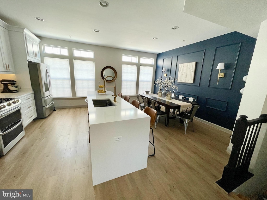 kitchen featuring a healthy amount of sunlight, light wood-style floors, stainless steel appliances, and a sink