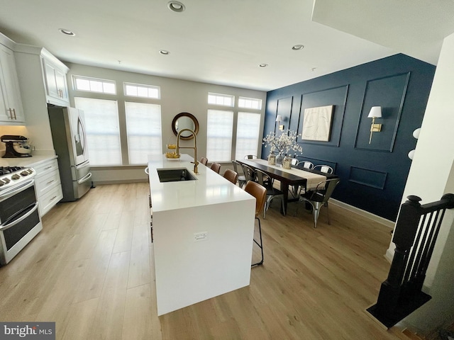 kitchen with plenty of natural light, light wood-style flooring, stainless steel fridge with ice dispenser, and range with two ovens