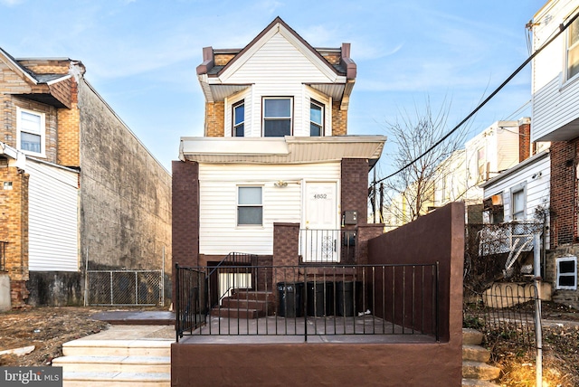 back of property featuring a fenced front yard and brick siding