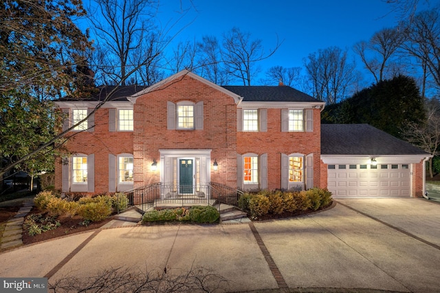 colonial house featuring brick siding, concrete driveway, a garage, and a shingled roof