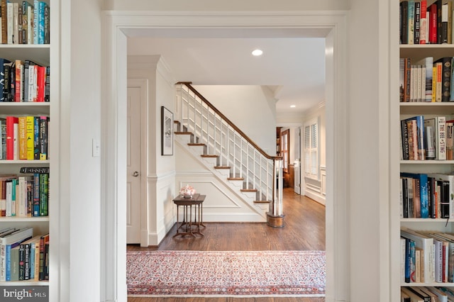 hall featuring stairway, built in shelves, wood finished floors, recessed lighting, and ornamental molding