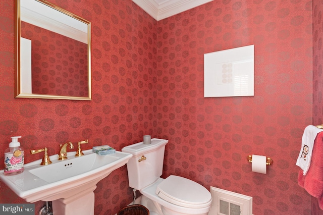 bathroom with visible vents, toilet, ornamental molding, a sink, and wallpapered walls