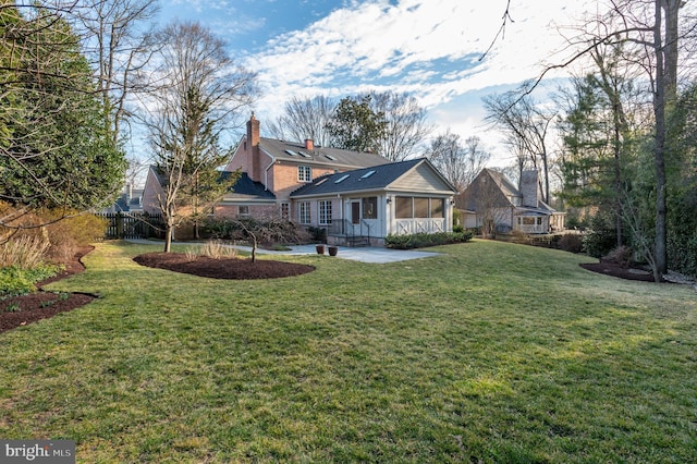 view of front of property featuring a chimney, a sunroom, a front yard, and fence