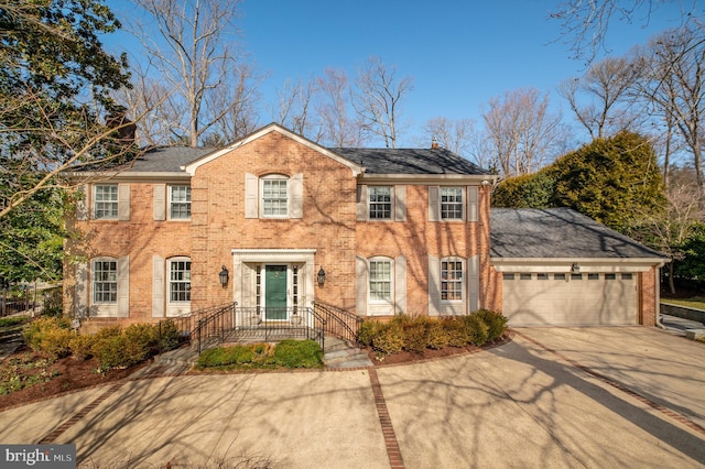 colonial house with concrete driveway, an attached garage, and brick siding