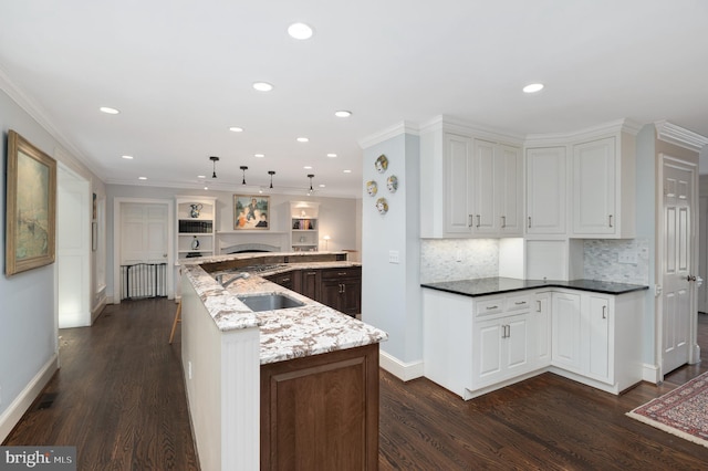 kitchen featuring a sink, light stone counters, dark wood-type flooring, and ornamental molding