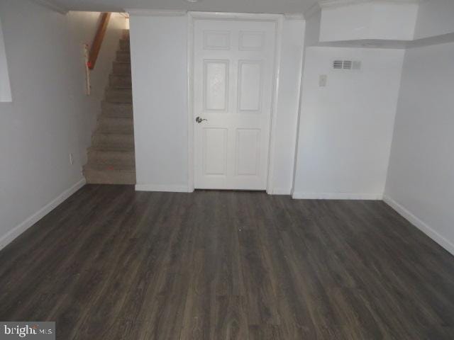 below grade area with stairway, dark wood finished floors, and baseboards