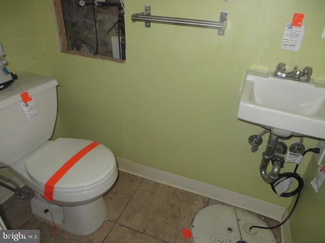 half bathroom with tile patterned flooring, baseboards, and toilet