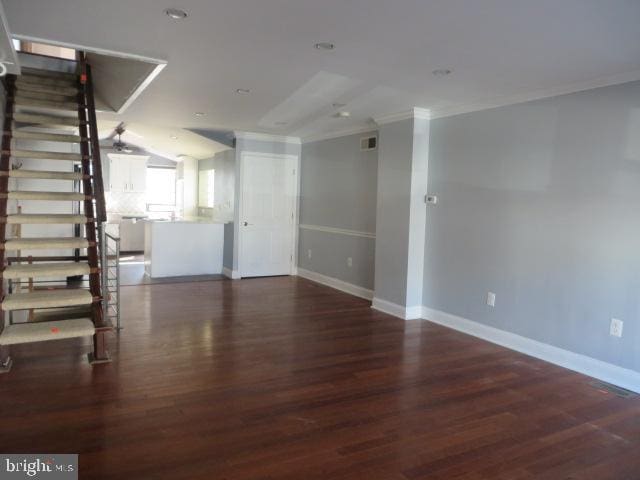 unfurnished living room with ornamental molding, dark wood-style flooring, stairway, and baseboards