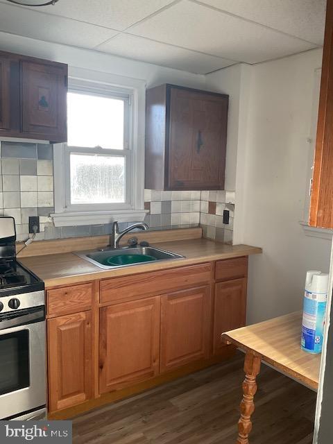 kitchen with brown cabinets, light countertops, a sink, and gas stove