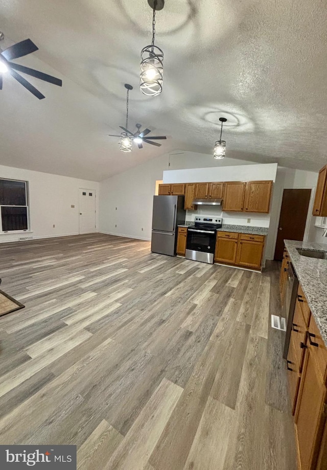 kitchen with pendant lighting, appliances with stainless steel finishes, brown cabinetry, ceiling fan, and under cabinet range hood