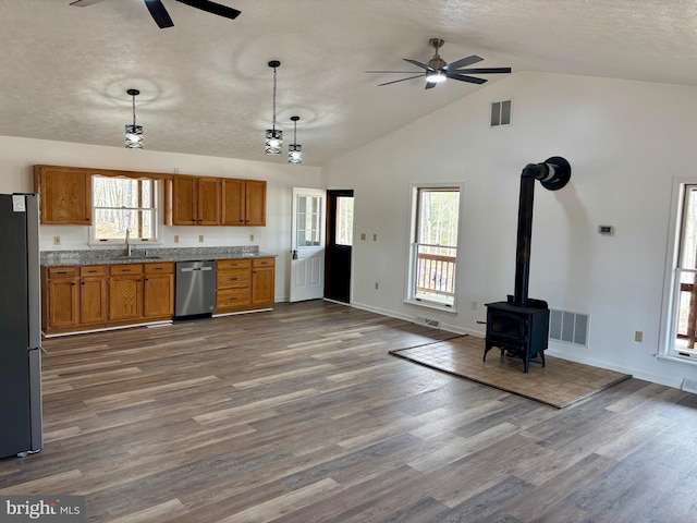 kitchen featuring stainless steel appliances, brown cabinetry, a sink, and visible vents