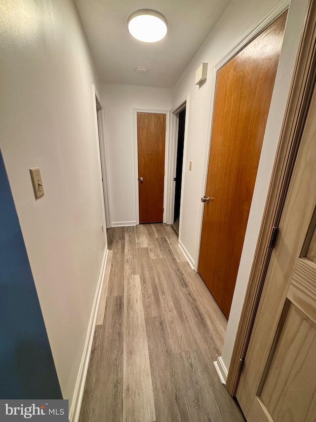 hall with baseboards and wood finished floors