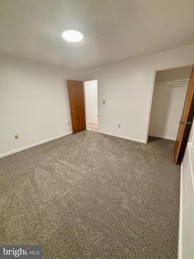 unfurnished bedroom with carpet floors, a closet, and baseboards