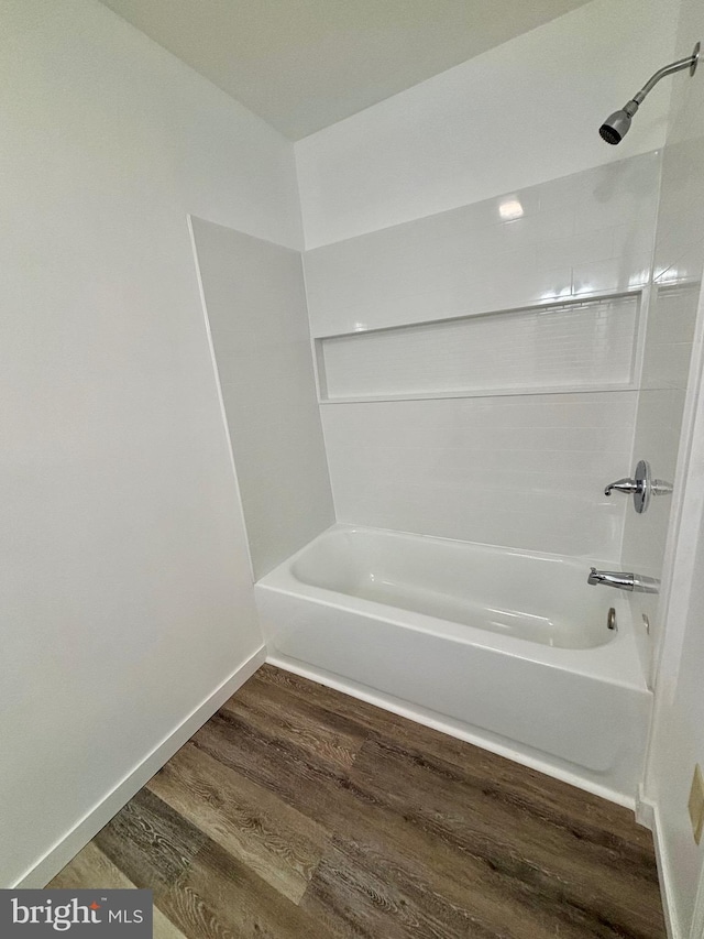 bathroom featuring shower / washtub combination, baseboards, and wood finished floors