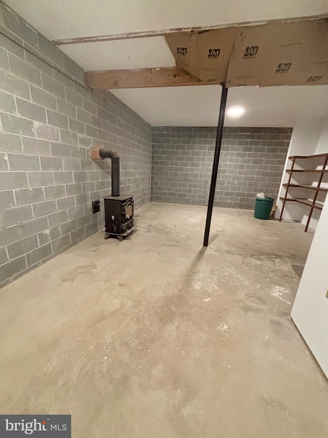 finished basement with concrete block wall and a wood stove