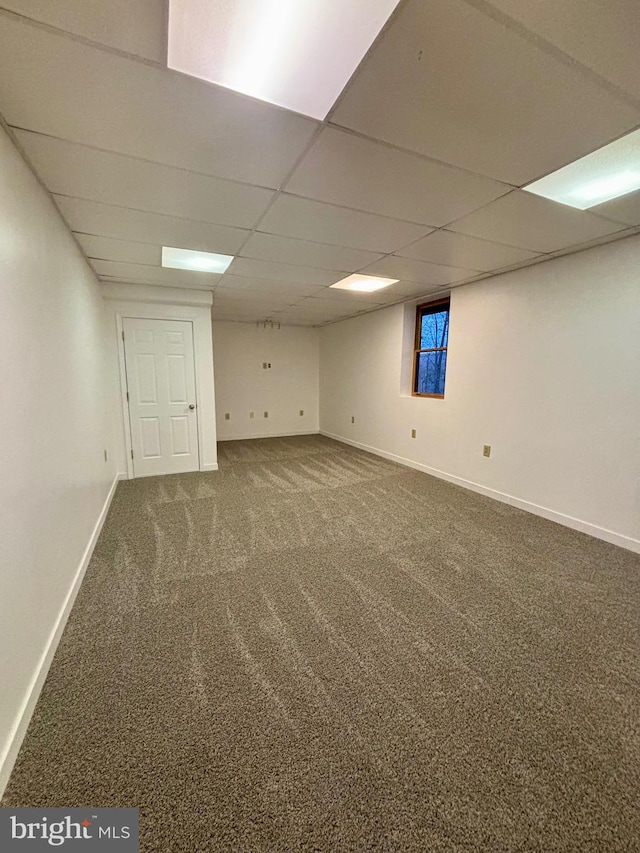 finished basement featuring a paneled ceiling, carpet, and baseboards