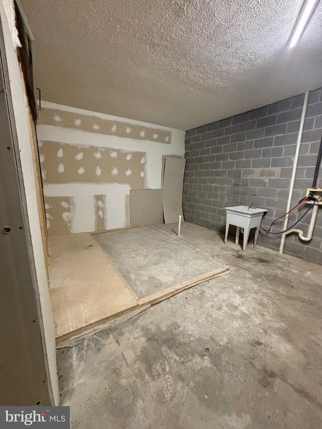 unfinished basement with a textured ceiling and concrete block wall