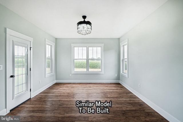 interior space featuring a notable chandelier, dark wood-style flooring, and baseboards