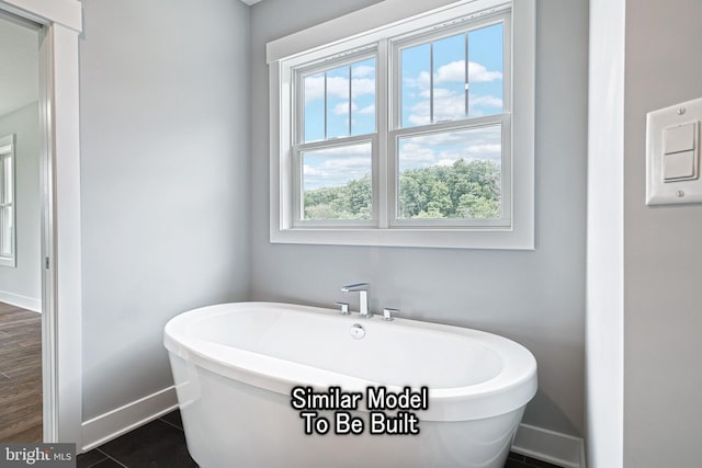 full bath featuring a soaking tub, tile patterned flooring, and baseboards