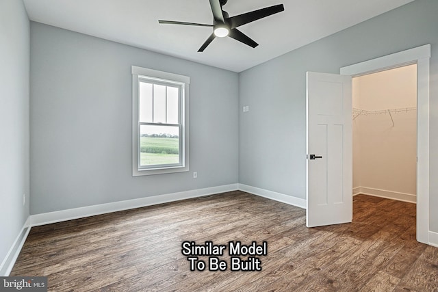 unfurnished bedroom featuring dark wood-style floors, a closet, a spacious closet, and baseboards