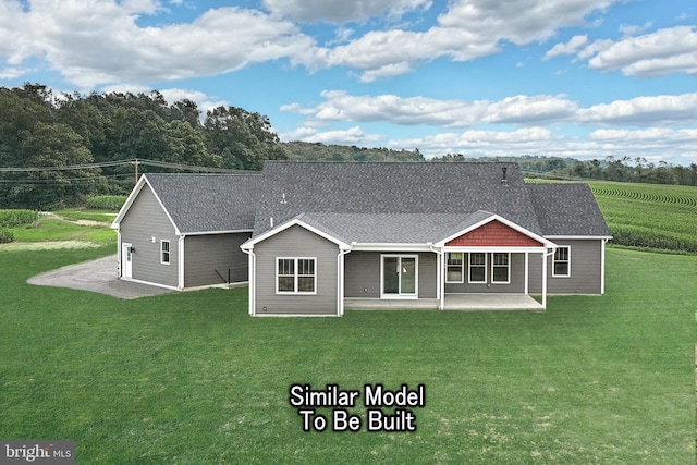 view of front of house with roof with shingles, a patio, and a front lawn