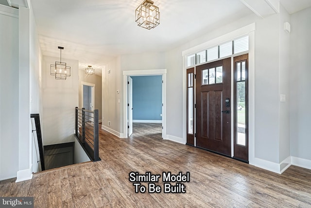 foyer entrance with a chandelier, dark wood-style flooring, and baseboards