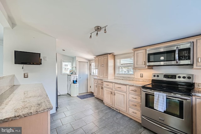 kitchen with lofted ceiling, light brown cabinets, stainless steel appliances, light stone countertops, and rail lighting