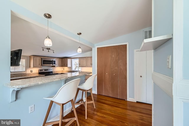 kitchen with visible vents, appliances with stainless steel finishes, decorative light fixtures, a peninsula, and a kitchen bar