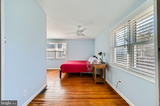 bedroom featuring a ceiling fan, wood finished floors, visible vents, and baseboards