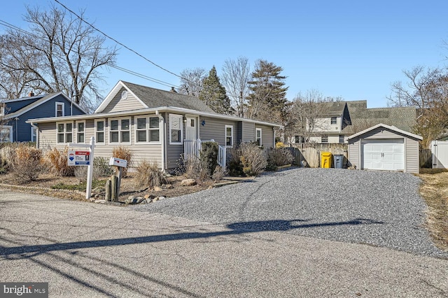 view of front facade with gravel driveway, a garage, and an outbuilding