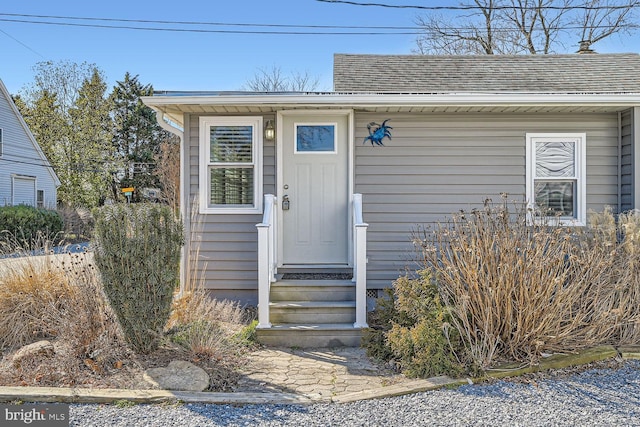 entrance to property featuring a shingled roof